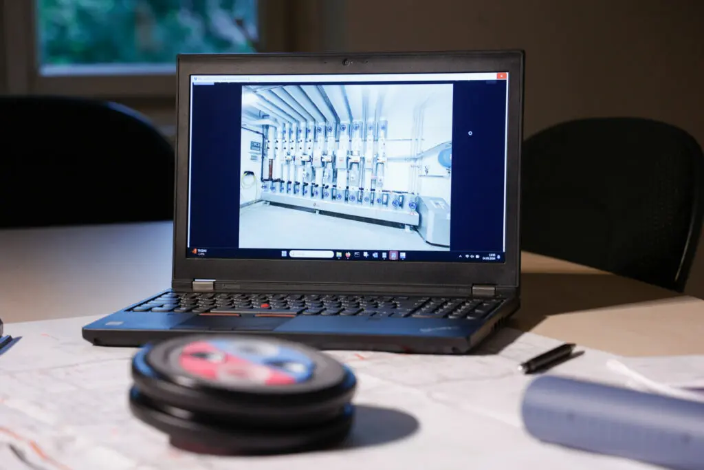 Laptop zeigt Foto eines Technikraums mit Rohrleitungen