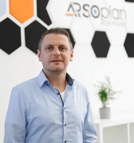 David Raitza im ARSOplan-Büro vor dem Firmenlogo